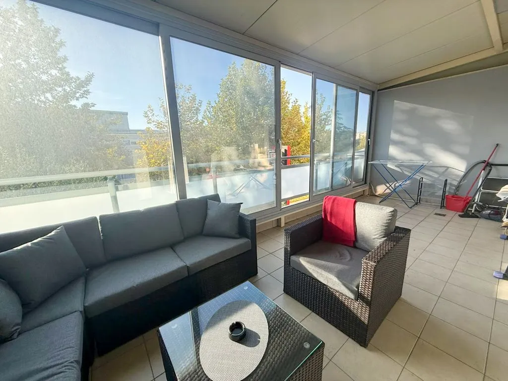 Enclosed terrace with lounge furniture and a drying rack.