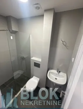 Moderno opremljeno kupatilo sa tuš kabinom i sivim pločicama. - image 9
