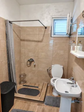 Bathroom equipped with a shower cabin, washbasin, and toilet. - image 10