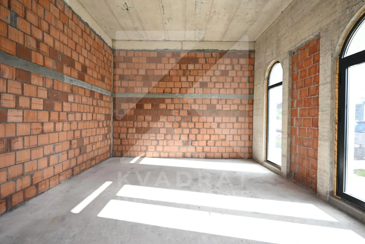 Unfinished room under construction with brick walls and arched windows.
