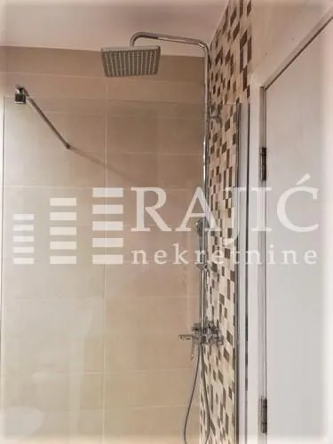 View of the shower cabin with modern fixtures and tiles in the bathroom.