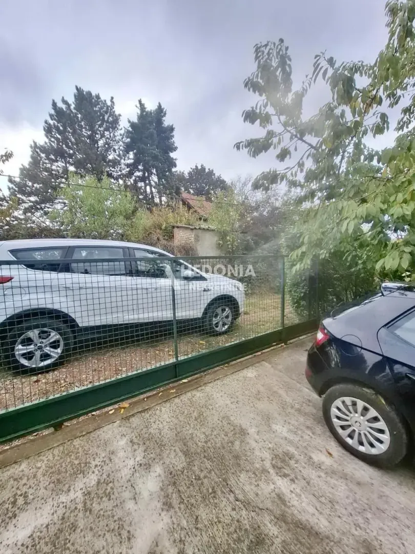 Dvorište sa kapijom i parkiranim automobilom.
