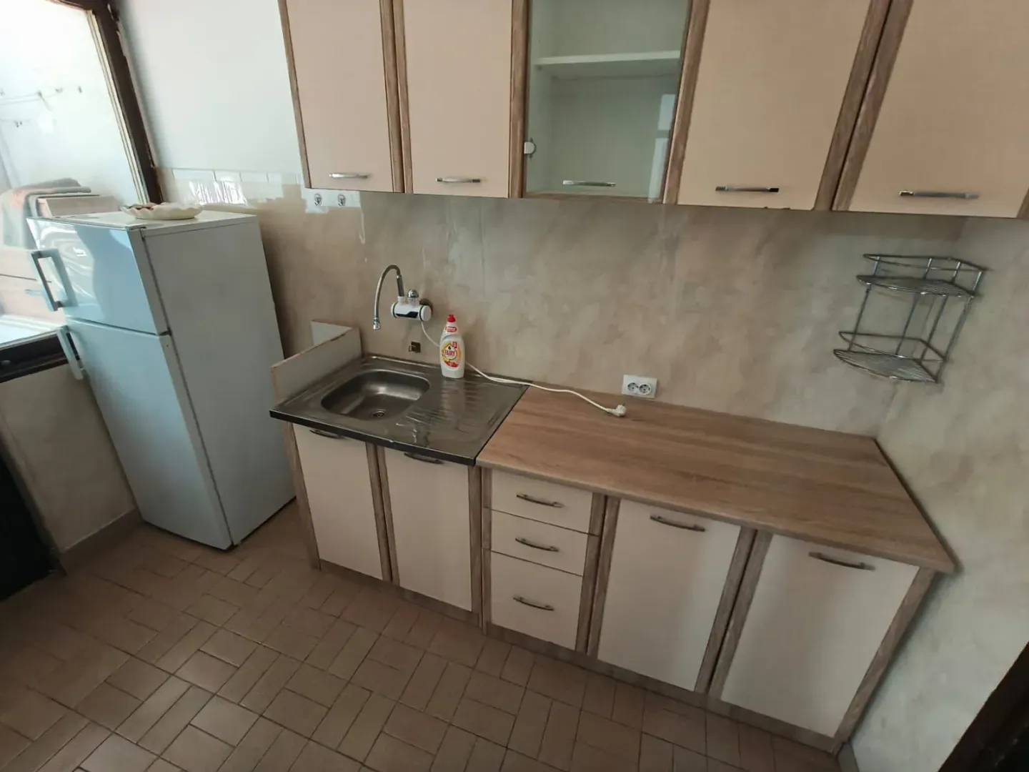 Small kitchen with a sink, cabinetry, and a refrigerator.