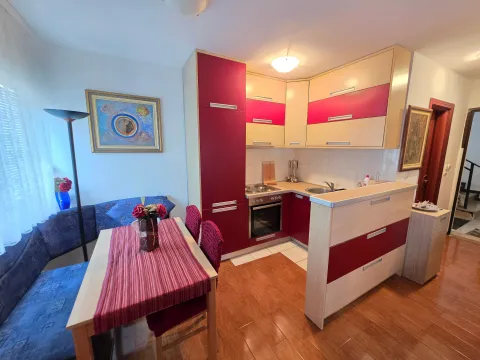 Trpezarija sa kuhinjom opremljena drvenim elementima i stolom za ručavanje. - image 5