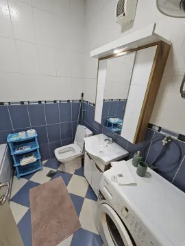 Kupatilo sa plavo-bijelim pločicama, lavaboom i veš mašinom. - image 14