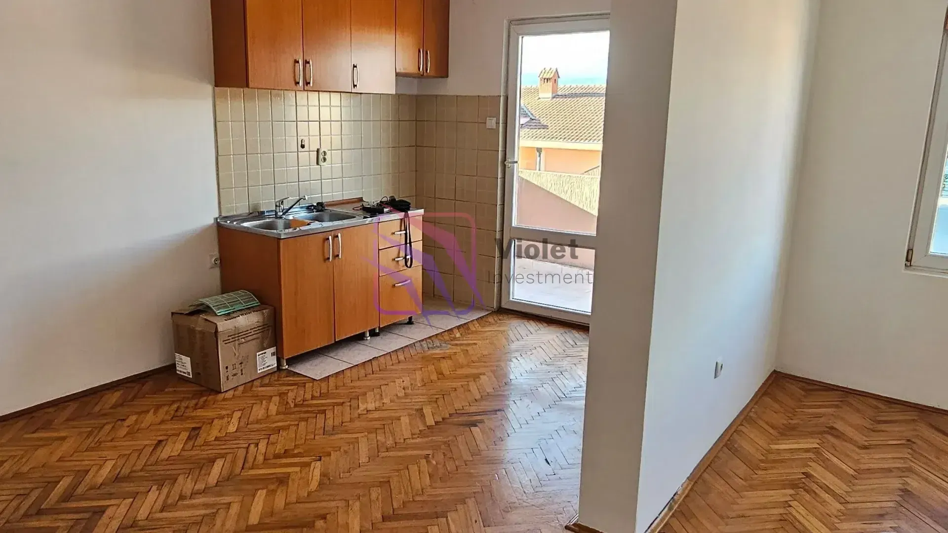 Manja kuhinja sa drvenim elementima i izlazom na terasu.