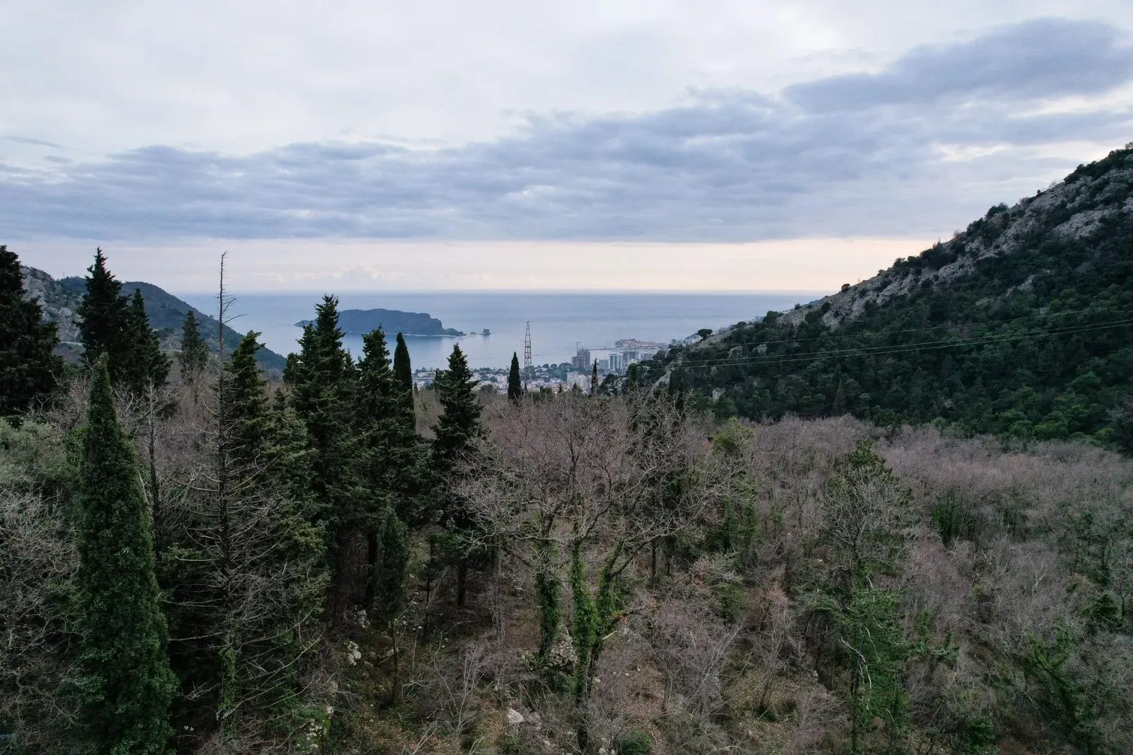 Panoramski pogled na more i okolna brda sa šumovitim predjelom.