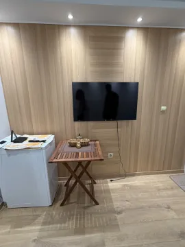 Living room with wooden wall paneling, a television, and a small table. - image 12