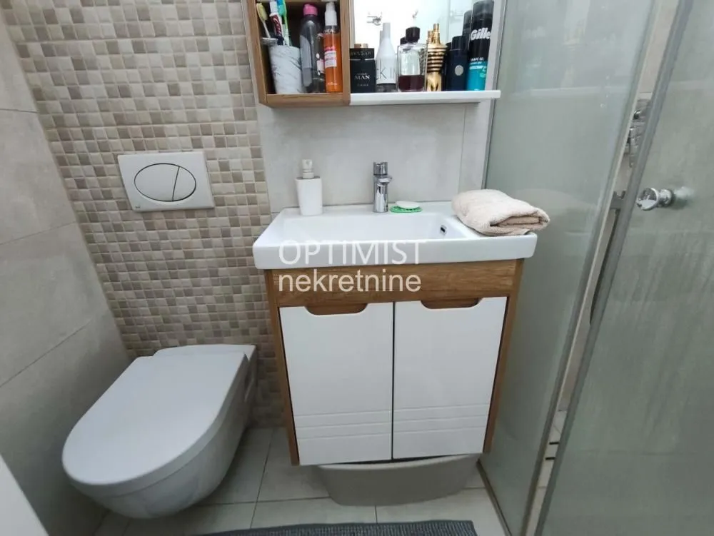 Manje kupatilo sa umivaonikom, WC šoljom i zidnim elementom.
