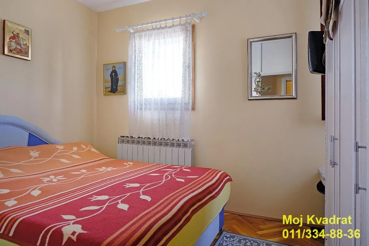 Manja spavaća soba sa bračnim krevetom, prozorom i garderoberom.