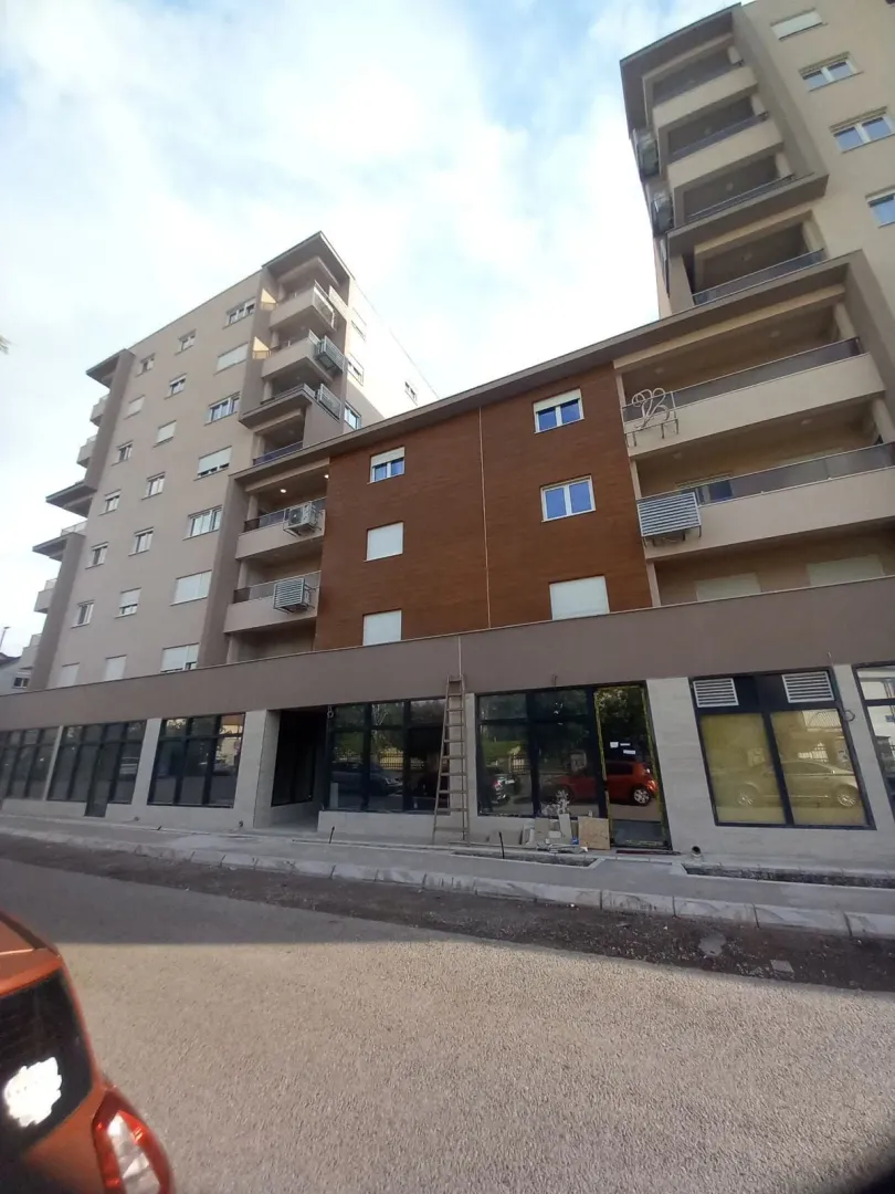Pogled na spoljašnjost moderne stambene zgrade sa poslovnim prostorom u prizemlju.