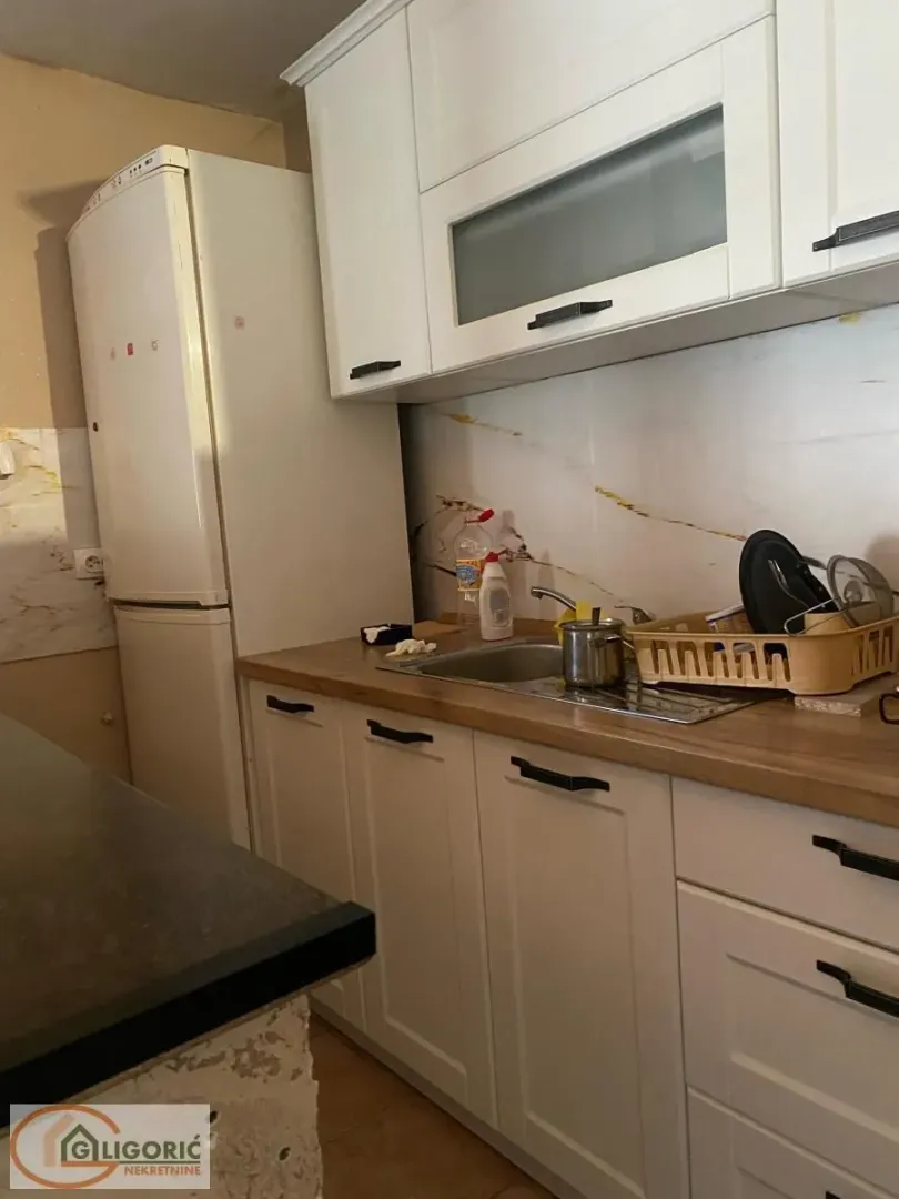 Smaller kitchen with white cabinets, a sink, and a refrigerator.