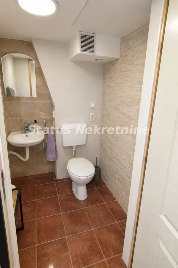 Smaller bathroom with a washbasin, toilet, and ceramic tiles.