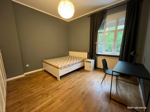 Furnished bedroom with a bed, desk, and window. - image 6
