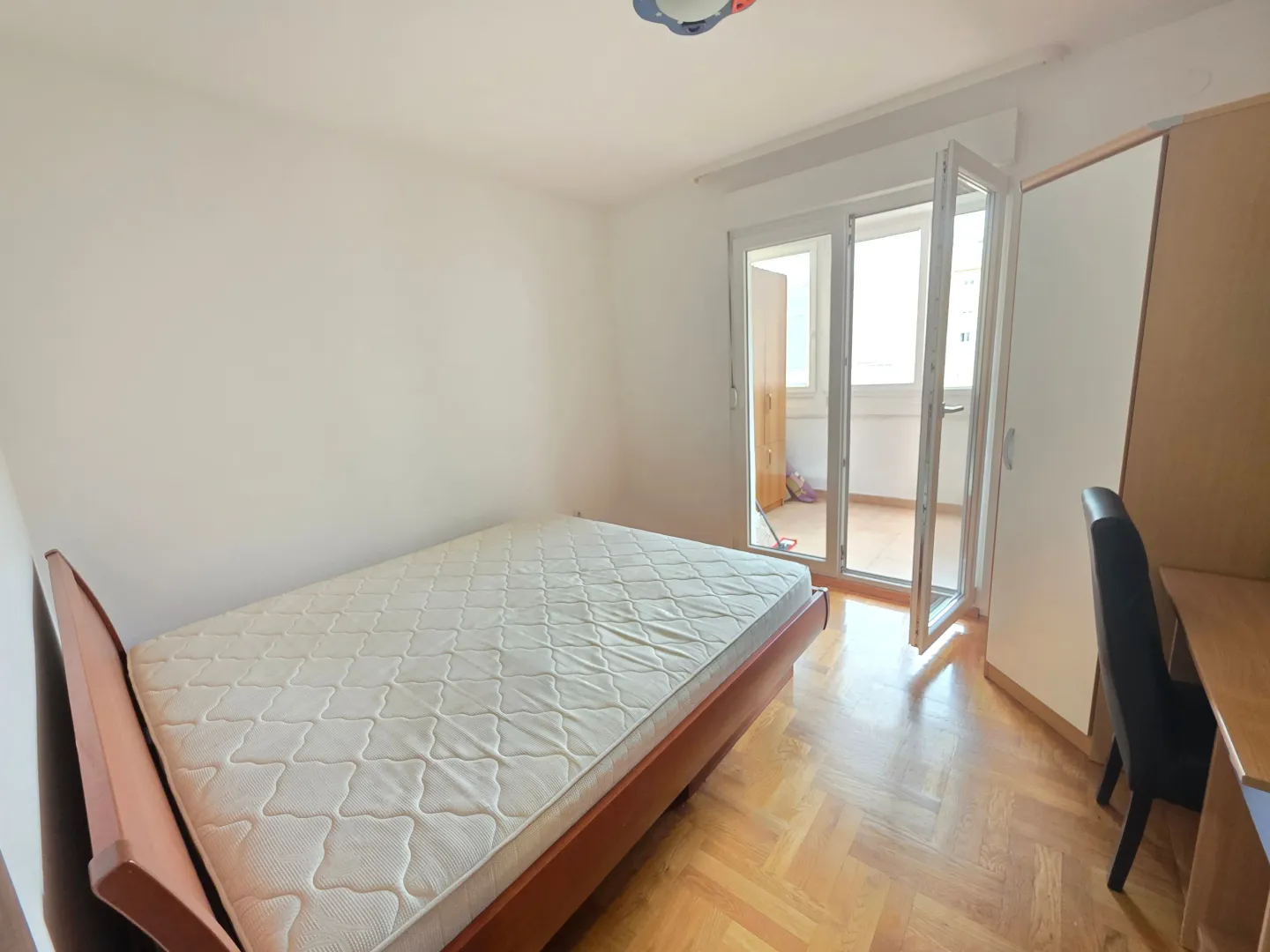 Spavaća soba sa bračnim krevetom, radnim stolom i izlazom na terasu.