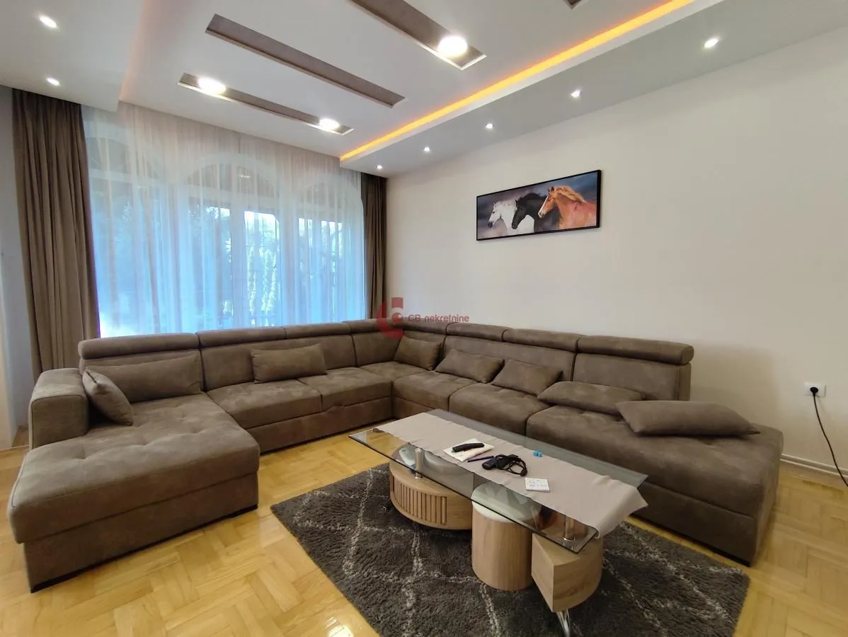 Living room with a sectional sofa, coffee table, and recessed ceiling lighting.