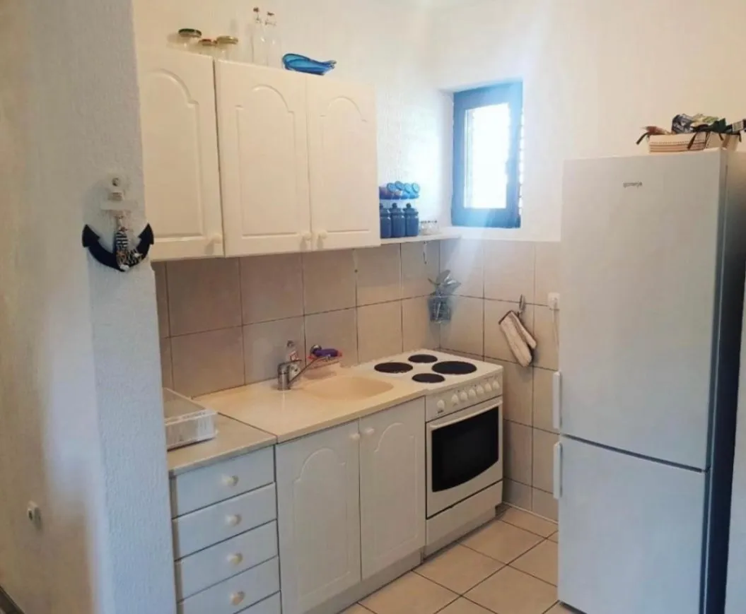 Small white kitchen with a stove and refrigerator.