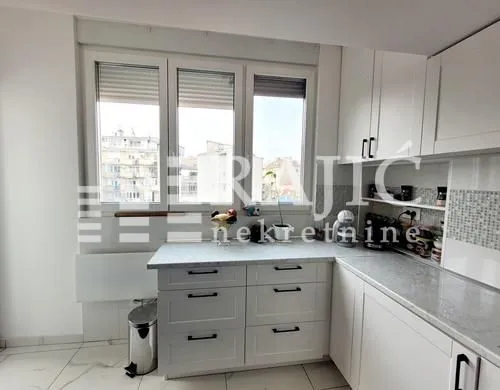 Modern white kitchen with a window and city view.