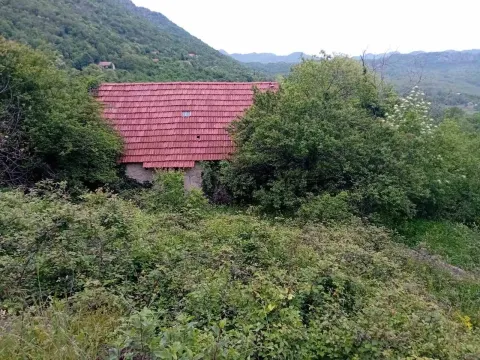 Kamena kuća sa crvenim krovom okružena bogatim zelenilom u planinskom predjelu. - image 3
