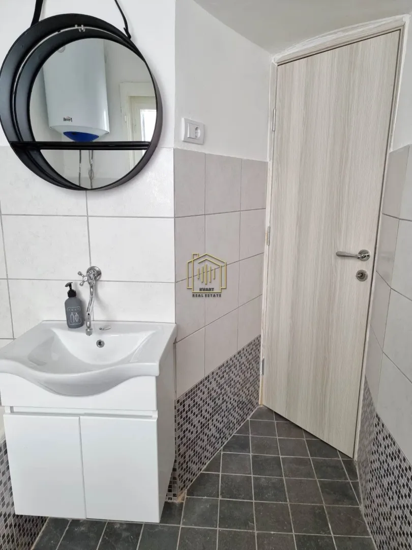 Small bathroom with a washbasin, mirror and a door.