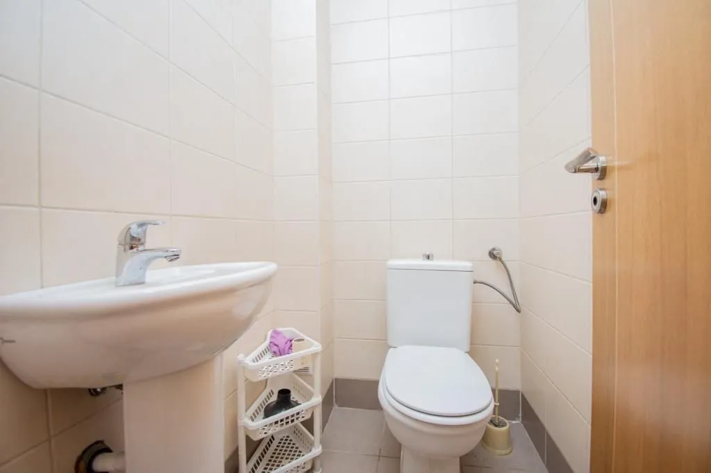 A small bathroom with a toilet, sink, and light-colored tiles.