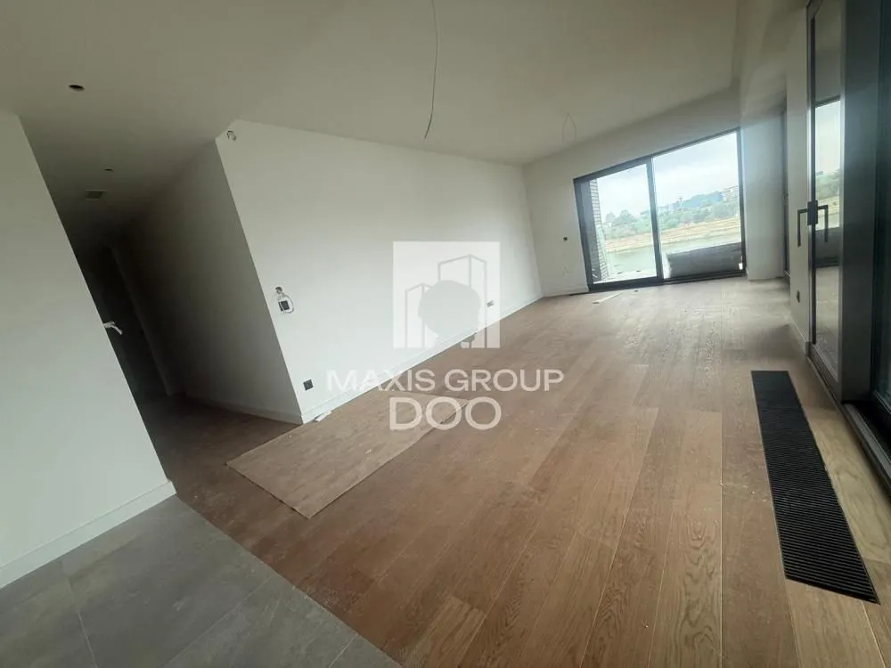 Empty living room with wooden flooring and large glass surfaces.