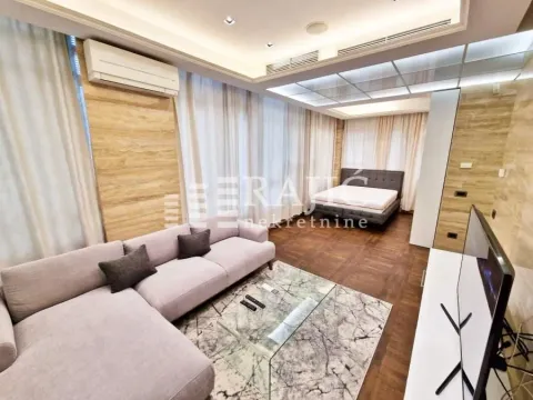 Spacious living room with a sofa and a double bed in the background. - image 3