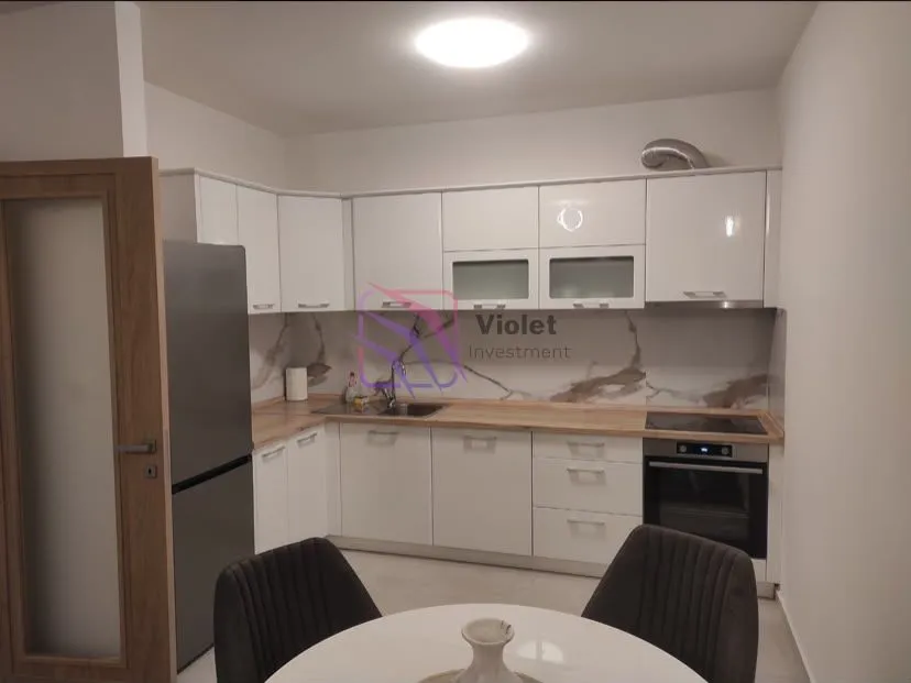 Modern white kitchen with built-in appliances and a dining table.