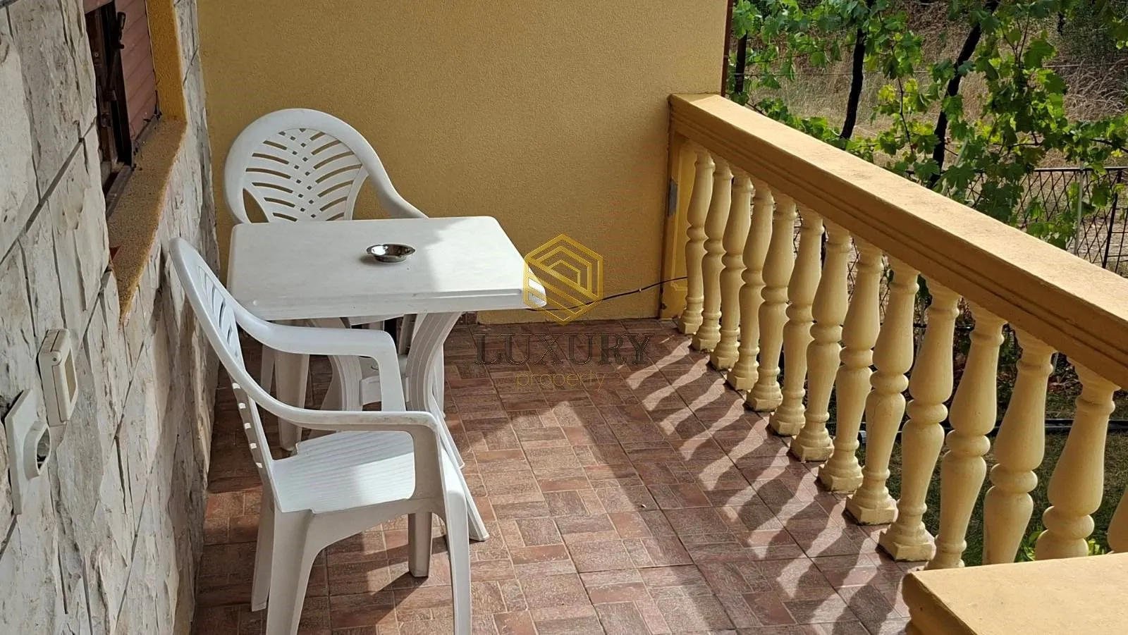 Manji namješteni balkon sa stolom, stolicama i dekorativnom ogradom.