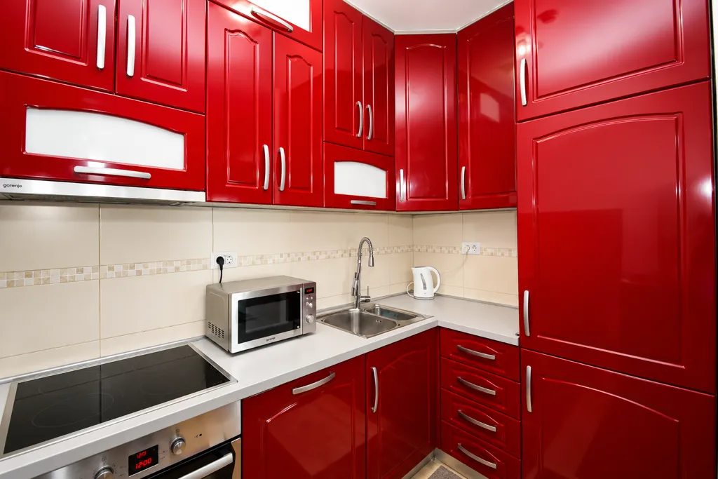 A modern kitchen with bright red cabinets and built-in appliances.