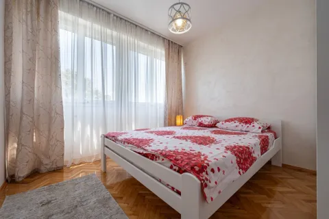 Bright bedroom with a double bed, parquet flooring, and a large window. - image 6