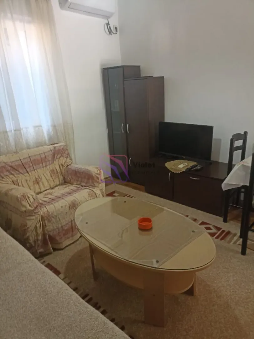 Living room with sofa, television, and dining table.