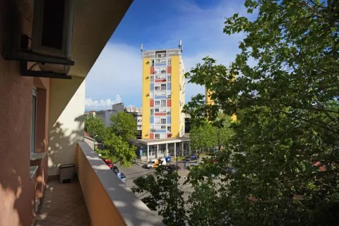 View from the balcony overlooking surrounding buildings and trees. - image 9
