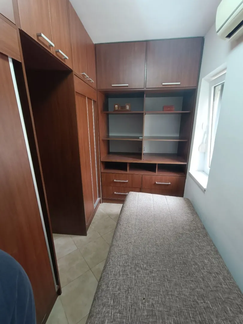 Mala spavaća soba sa velikim ugradnim drvenim plakarima i jednim krevetom.