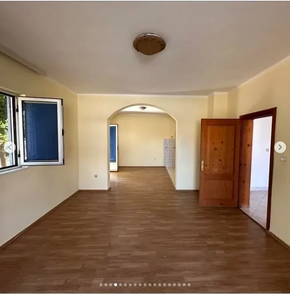 Prostrana prazna prostorija sa svijetlim zidovima, laminatom i lučnim prolazom.
