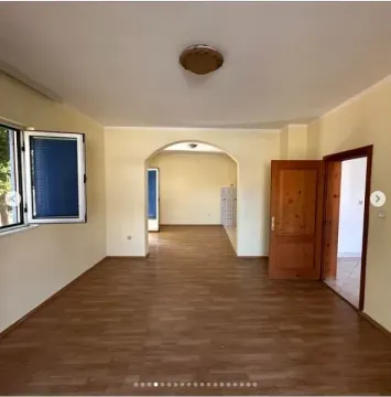 Prostrana prazna prostorija sa svijetlim zidovima, laminatom i lučnim prolazom. - image 3