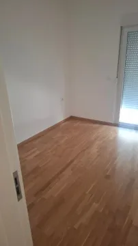 Prazna soba sa parketom i balkonskim vratima. - image 2
