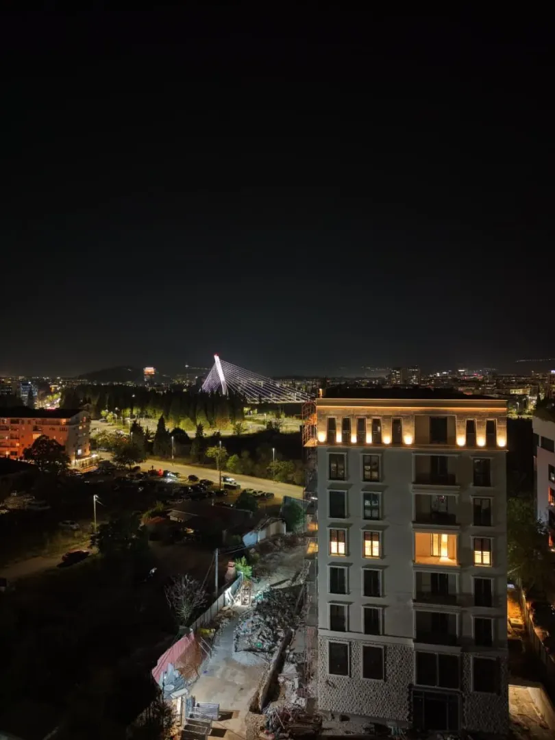 Noćni pogled sa terase na grad i osvijetljeni most.