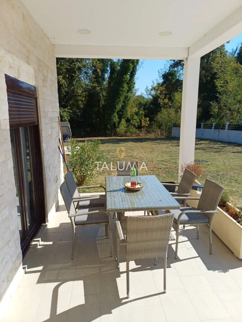 Covered terrace with a table and chairs and a view of the yard.