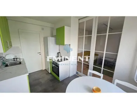 Small kitchen with white and green cabinets and a dining table in the foreground. - image 3