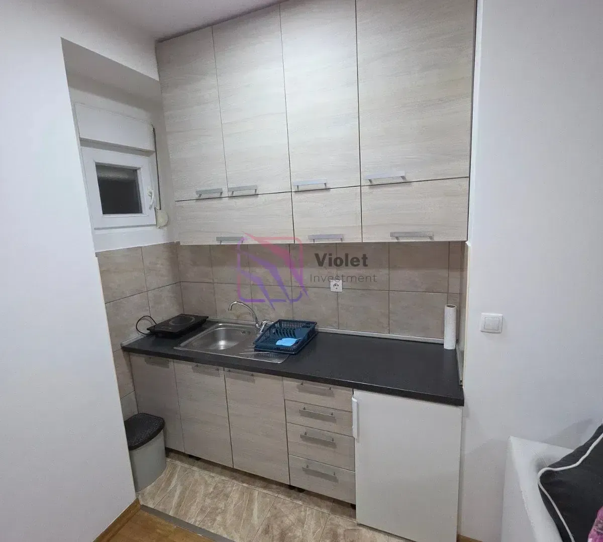 Small kitchen with wooden cabinetry and a sink.