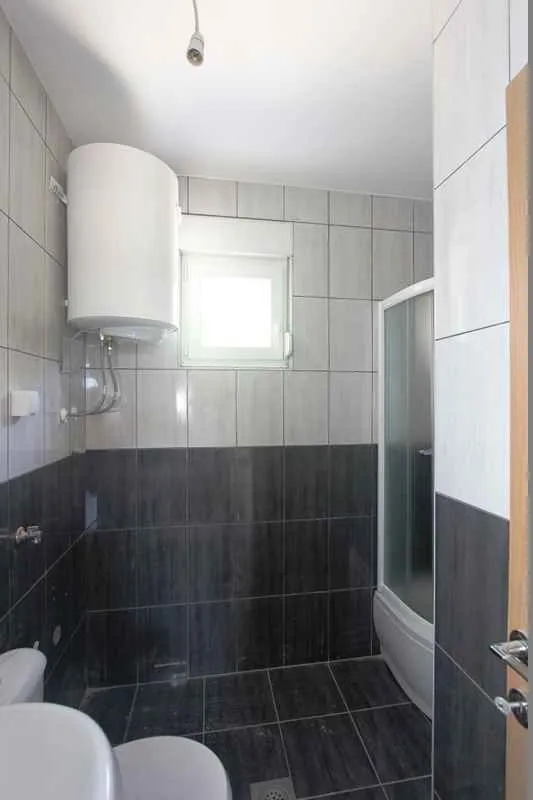 Kupatilo opremljeno tuš kabinom, sanitarijama i bojlerom.