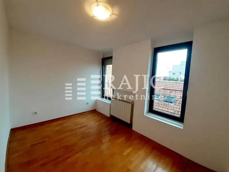 Empty room with parquet flooring and a window.