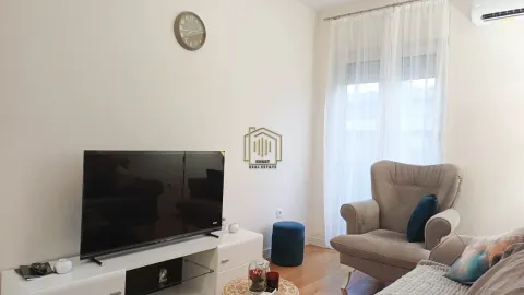 Dnevna soba sa foteljom, TV-om i bijelom komodom. - image 2