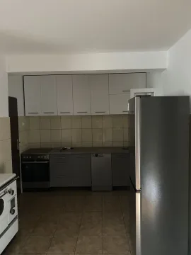 Simple kitchen with grey cabinets, white upper cupboards, and a large refrigerator. - image 3