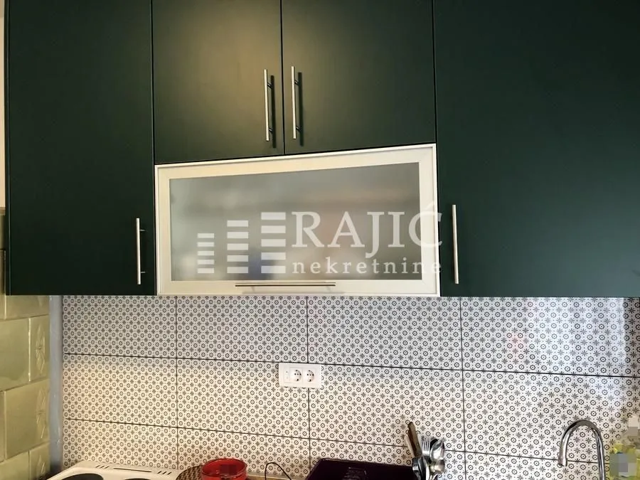 Part of the kitchen with dark cabinets and ceramic tiles.