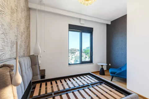 Spavaća soba sa modernim ramom za krevet, plavom foteljom i pogledom kroz prozor. - image 6