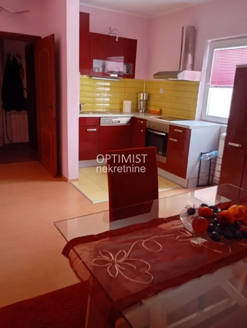 Kitchen combined with a dining area featuring red cabinets and yellow tiles.