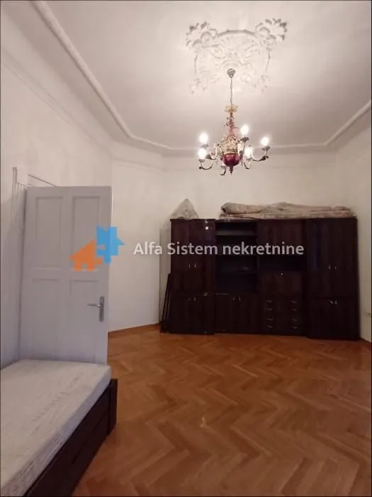 Bedroom with a bed, a wooden wardrobe, and parquet flooring.