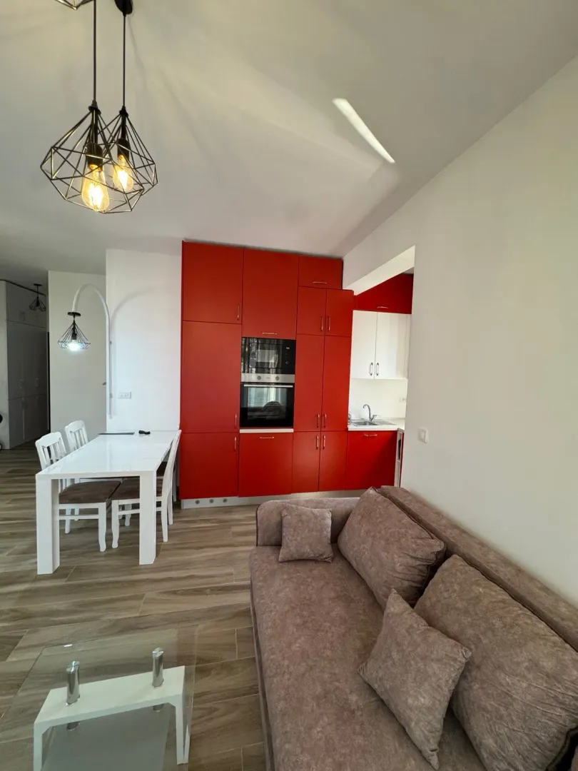Living room connected with the dining area and kitchen featuring red cabinets.